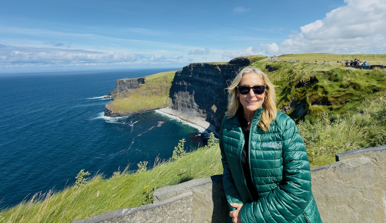 Lisa Solomon in a green jacket on a clifftop at the Cliffs of Moher during her Ireland guided tour