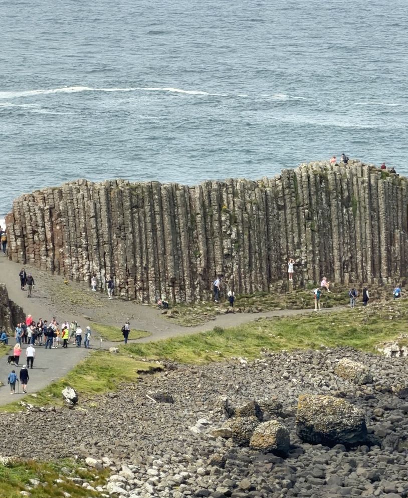 Stone columns at the Giant's Causeway in Northern Ireland, with visitors on the path and the sea beyond